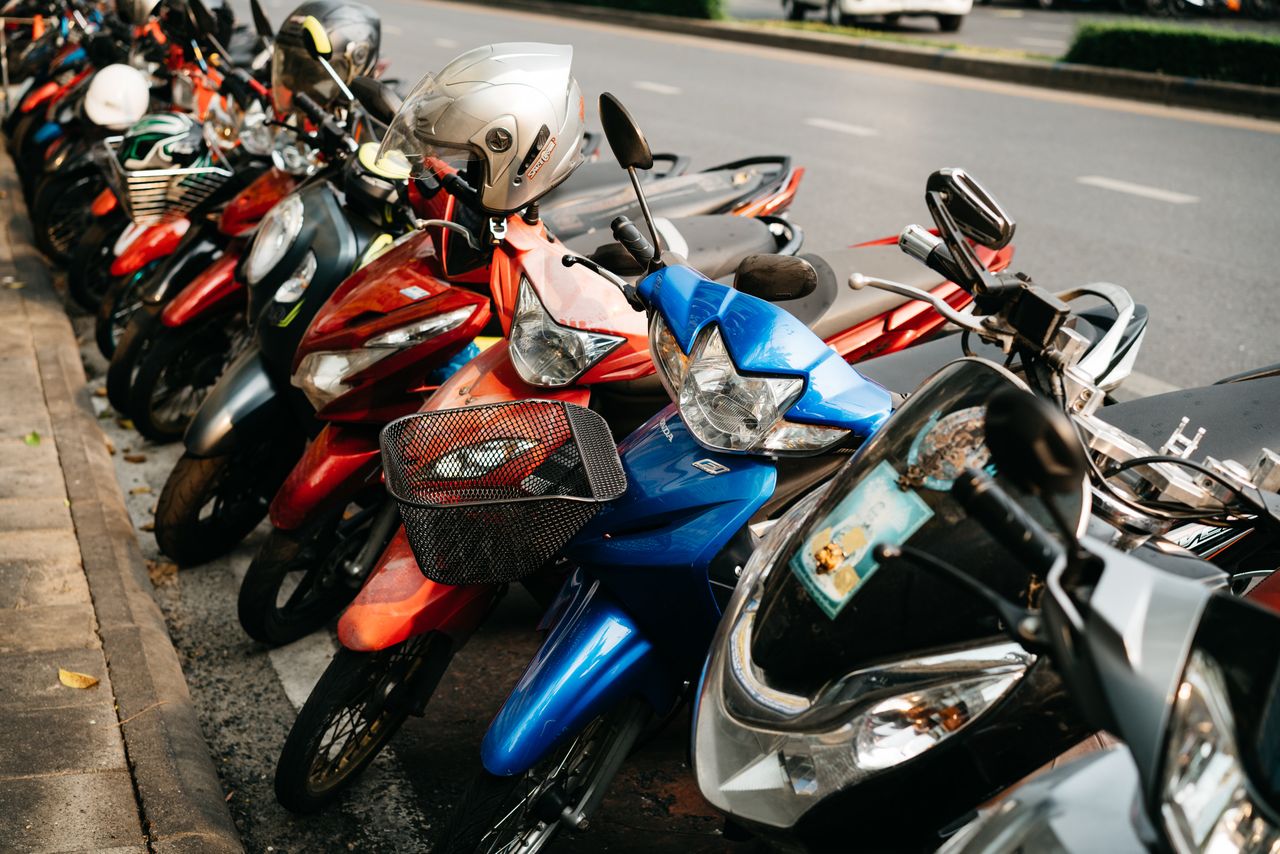 A vibrant lineup of parked motorbikes on an urban street, showcasing diverse colors.